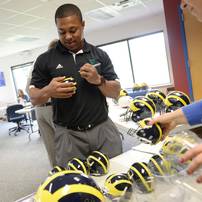 Former Michigan football player and current EMU football running backs coach Mike Hart autographs mini football helmets before hitting the airwaves during the Mott Takeover at 1050 WTKA on Friday, May 17, 2013. Melanie Maxwell I AnnArbor.com